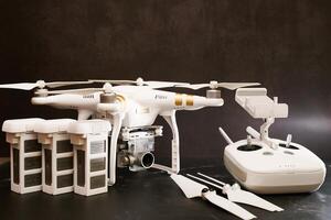 USA, Arizona - March 10, 2025. White DJI Phantom 3 drone with spare batteries, propellers and a control panel stands on a black table photo