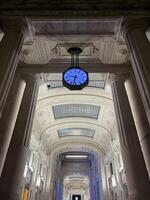 Milan, Italy - 12 november 2023. Illuminated clock hangs from the marble ceiling of an ancient building photo