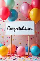 Congratulations sign surrounded by colorful balloons and confetti for celebration photo
