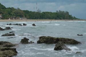 A beach with people playing in the water on a cloudy day photo