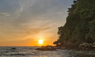 Sunset at the beach with a high cliff as the foreground photo