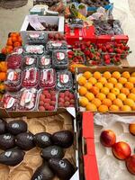Budva, Montenegro - 25 december 2022. Avocados, peaches, lychee berries, raspberries, strawberries lie in boxes on the market photo