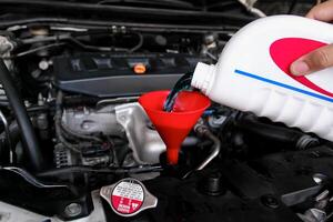 Pouring coolant fluid using a funnel into car radiator , Car maintenance concept photo
