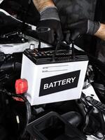 Car battery replacement , Automotive repair concept. Hands installing a car battery in a vehicle engine bay. Indoor shot of garage. photo