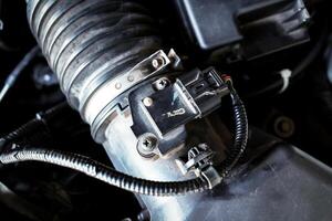 Close-up of automotive mass airflow sensor on air intake manifold of car combustion engine , Automotive parts concept photo
