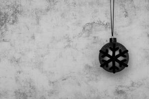 A hanging snowflake ornament against a textured gray wall photo