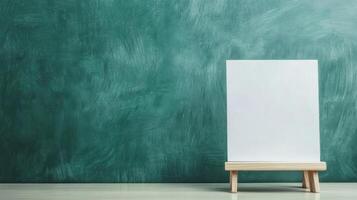 A blank white canvas on a small wooden stand against a textured green wall photo