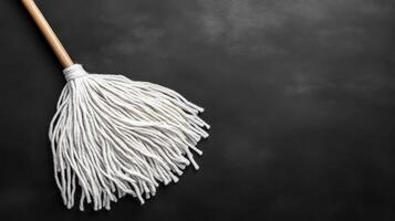 A cleaning tool with a wooden handle and white fibers on a dark surface photo