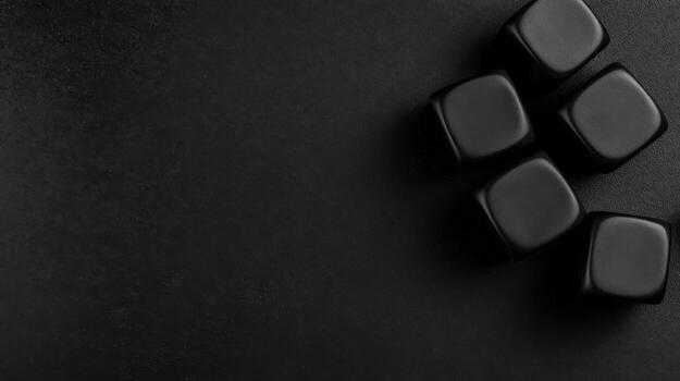 Five black unmarked cubes scattered on a dark surface photo