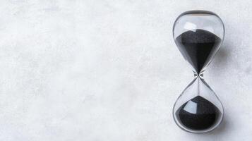 Glass Hourglass with Black Sand on a Light Surface photo