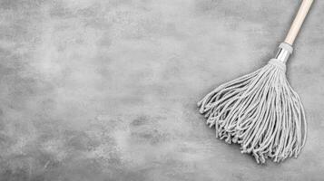 Mop with Wooden Handle on a Textured Gray Surface photo
