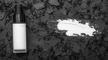 White Cosmetic Bottle with Black Cap on Dark Stone photo