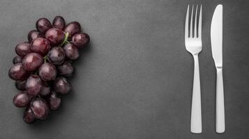 Bunch of Grapes with Silverware on Dark Surface photo