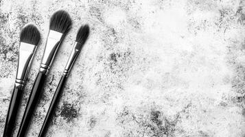 Three Makeup Brushes on Textured Gray Surface photo