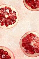 Red Pomegranate Halves on a Pink Textured Background photo