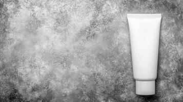 Plain White Cosmetic Tube on Mottled Gray Textured photo