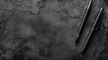 Two Black Pens on a Dark Textured Stone Surface photo