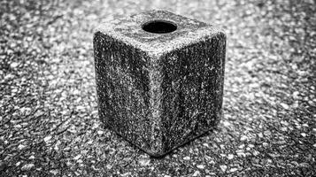 Monochrome Stone Cube with Central Hole on a Textured Surface photo