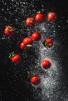 Scattered Cherry Tomatoes with Water Splashes on a Dark Surface photo