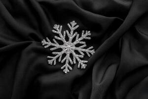 Silver Snowflake on Black Satin Fabric, Winter Symbol on Silky Textile photo