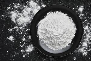 White Powder Pile in Black Round Bowl on Dark Surface photo