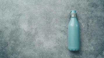 Sleek Cyan Water Bottle Resting on a Textured Gray Surface photo