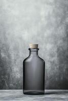 Dark Glass Bottle with Cork Stopper on a Textured Gray Surface photo