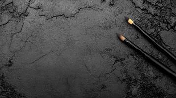 Two Black Paint brushes with Bristles on a Cracked Dark Stone Surface photo