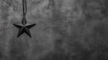 Black Star Pendant Hanging Against a Textured Dark Gray Surface photo