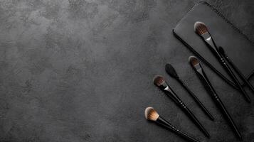 Assorted Makeup Brushes Scattered on a Dark Textured Surface photo