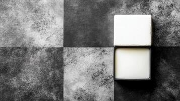 White Cream Jar with Lid on a Checkered Black and Gray Textured Surface photo