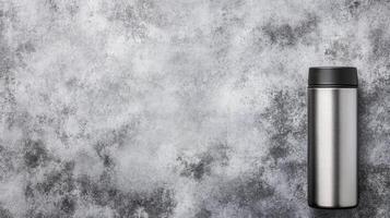Silver Thermos with Black Cap on a Mottled Gray Textured Surface photo