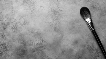 Black Makeup Brush on a Textured Gray Stone Surface photo