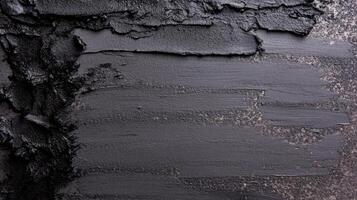 Thick Black Creamy Substance Smeared on a Dark Textured Surface photo