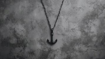 Black Anchor Pendant on a Chain Against a Textured Grayscale Stone Wall photo