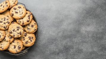 Chocolate Chip Cookies in a Black Basket on a Textured Grayscale Stone Surface photo