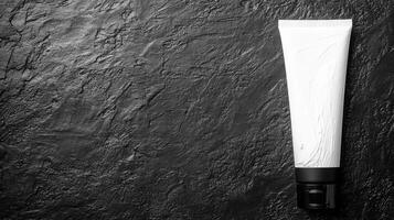White Cosmetic Tube on a Dark Textured Stone Surface in Minimalist Style photo