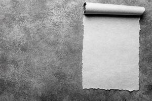 Torn Parchment Scroll on a Textured Dark Gray Surface in Monochrome photo