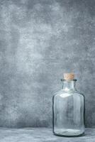 Clear Glass Bottle with Cork Stopper on a Textured Gray Surface photo