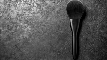 Black Makeup Brush with Fluffy Bristles on a Textured Dark Surface photo
