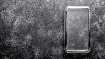 Empty Glass Baking Dish on a Textured Gray Surface in Monochrome photo