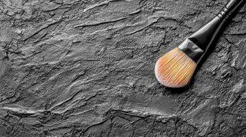 Black Makeup Brush with Soft Bristles on a Textured Dark Surface photo