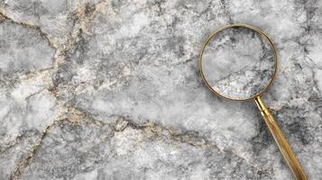 Gold Handled Magnifying Glass on a Textured Gray Marble Surface photo