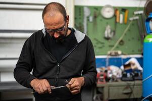 Conceptual photography about metal work, blacksmith is taking measurements of a metal bar with the use of caliper. Concept of reasoning at work, construction site in progress. photo