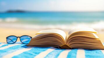 Open Book Lay on Beach Towel with Sunglasses Against Blurred Background of Ocean and Sky photo
