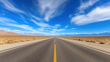 Expansive Open Desert Road Under Bright Blue Sky with Wispy Clouds and Mountain Range in the Distance photo
