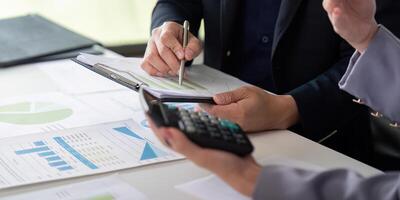 Collaboration and Financial Analysis. Colleagues discussing financial data with a calculator on the table. photo