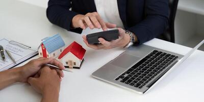 Real Estate Analysis and Investment Planning. An agent using a smartphone to discuss property prices with clients. photo
