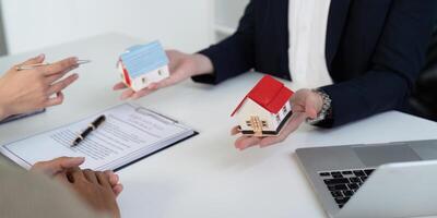 Property Choices and Real Estate Consultation. A couple discussing options with their agent while viewing house models. photo