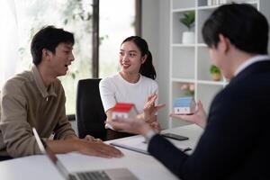 Engaging Real Estate Conversation. A couple discussing property options with their agent using house models. photo